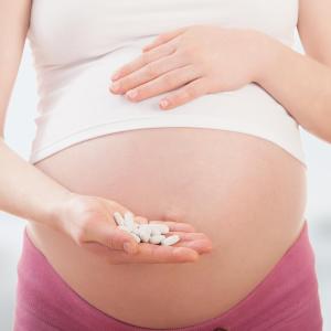 Беременная девушка держит таблетки