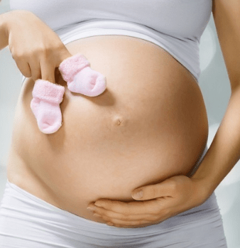 Беременная девушка держит в руках пинетки